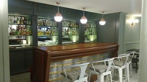 A bar area with a wooden counter, white bar stools, and shelves stocked with bottles. - Country Plaza (Zapopan)