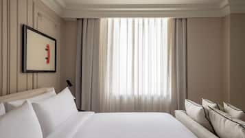 Habitación de hotel con una cama grande, un sofá, un cuadro en la pared y una ventana con cortinas.