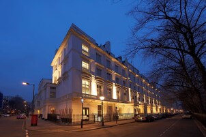A multi-story hotel with a classic architectural style, featuring a prominent entrance with a canopy and a series of windows on the ground floor.