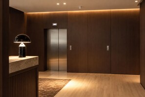 A modern elevator with a digital display, a marble counter with a lamp, and wooden paneling.