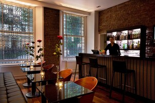 A bar area with a bartender, a glass display case, and a seating area with a table and chairs.