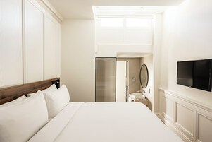 A hotel room with a large bed, a television mounted on the wall, and a bathroom visible through an open door.