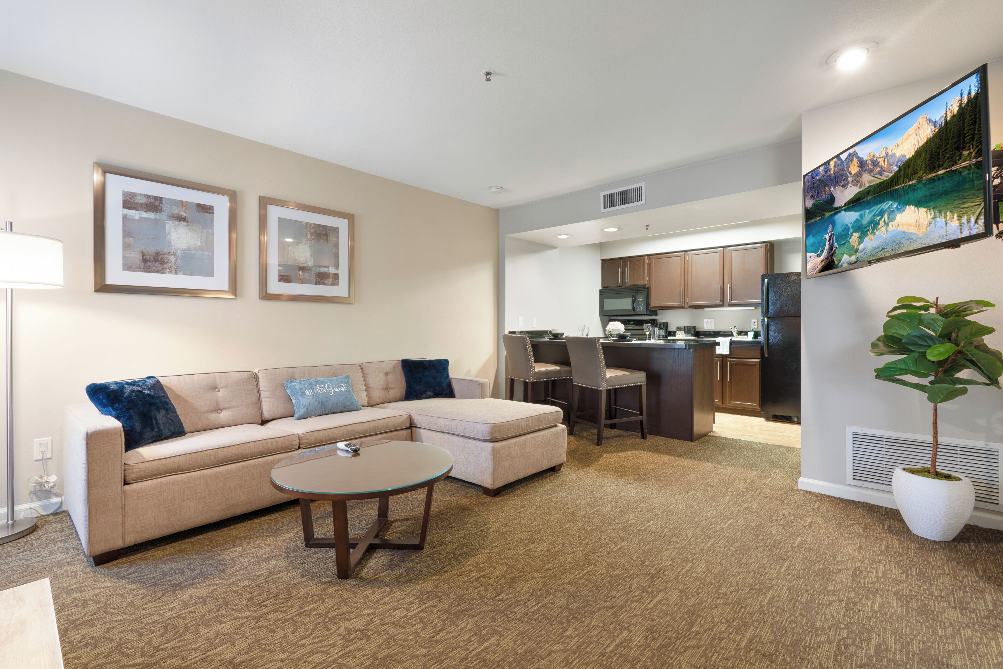 A modern living room with a sofa, coffee table, and a kitchen in the background.