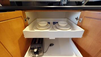 A kitchen with a built-in shelf holding two bowls and plates, a toaster, and a power outlet.