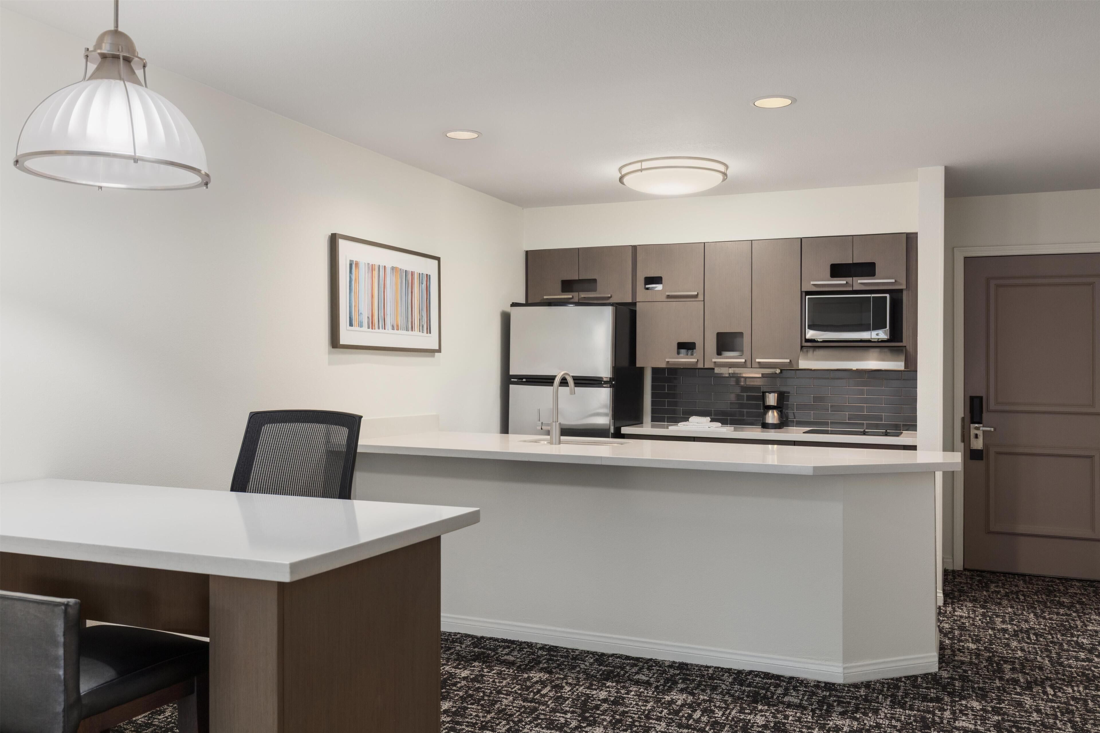 A modern kitchen with a central island, built-in appliances, and recessed ceiling lighting.