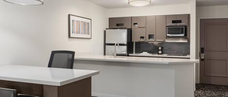 A modern kitchen with a central island, built-in appliances, and recessed ceiling lighting.