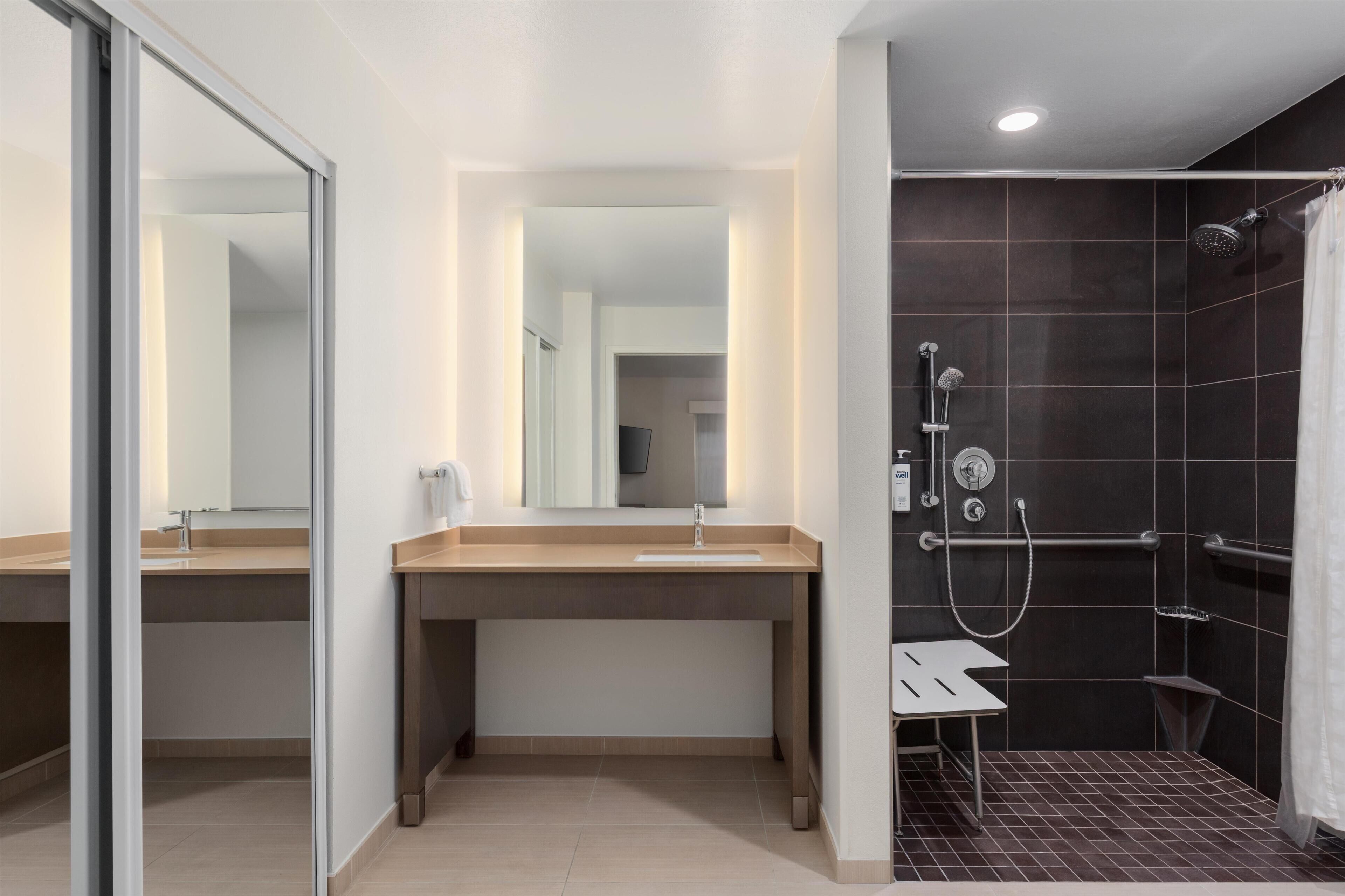 Une salle de bain moderne avec une douche à parois de verre, un meuble-lavabo avec miroir et un lavabo séparé.