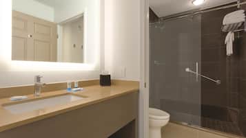 Une salle de bain avec un grand miroir, un lavabo et un espace douche.