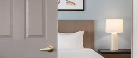 Une chambre d’hôtel avec un lit, une table de chevet avec une lampe et un tableau encadré au mur.