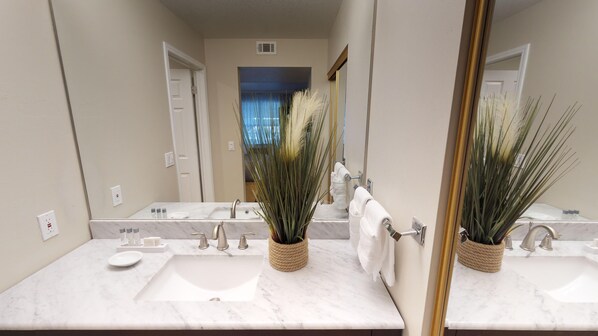 Un baño con dos lavamanos, un espejo grande y plantas decorativas.