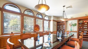A dining area with a glass table, wooden chairs, and a bookshelf with books and decorative items.