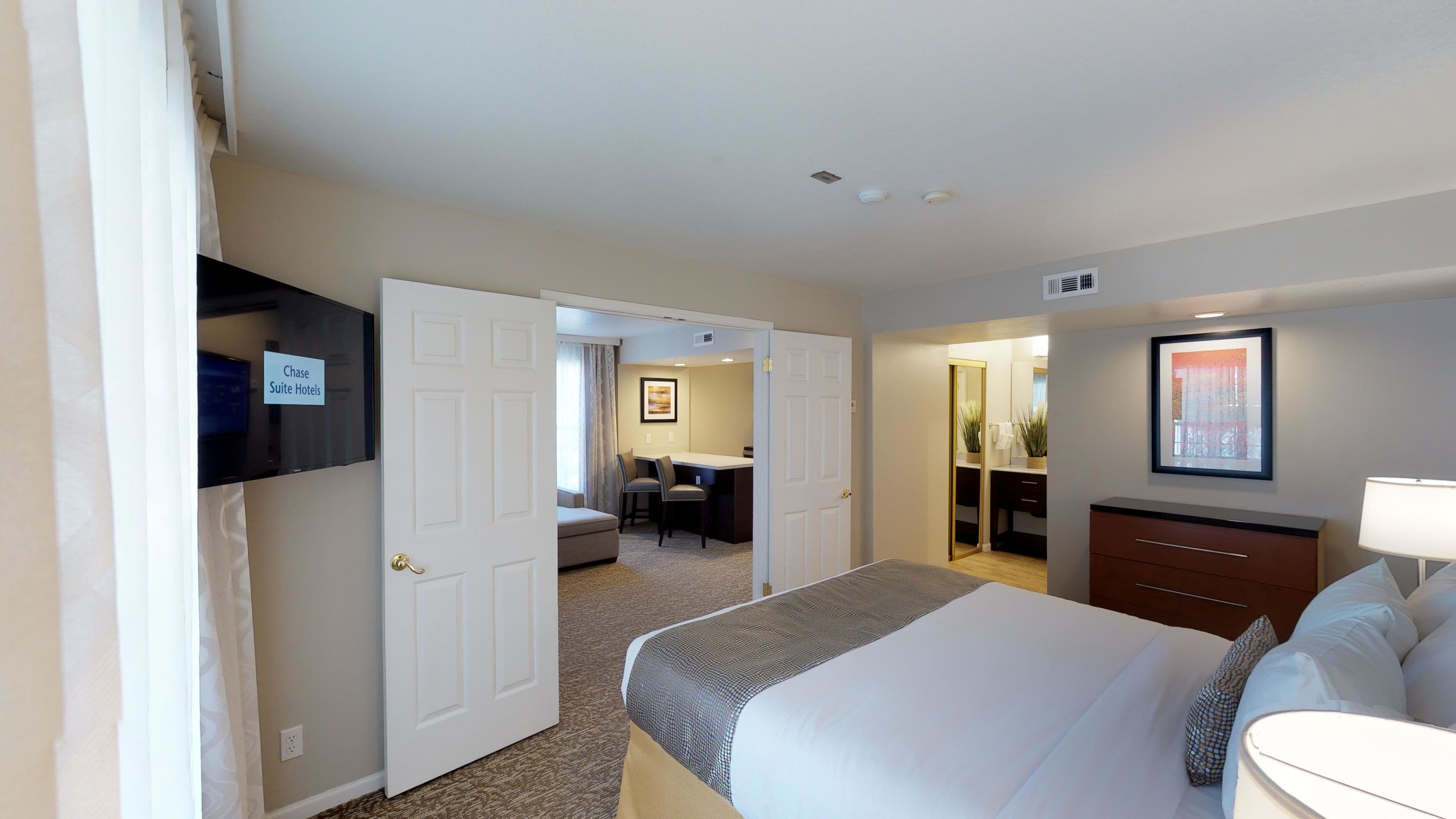 A hotel room with a bed, a desk, and a bathroom.