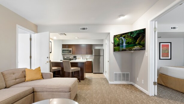 A modern living room with a sofa, a coffee table, and a kitchen in the background.