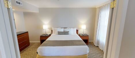 A hotel room with a large bed, two bedside tables with lamps, a telephone, and a wardrobe.