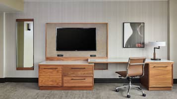 Habitació d'hotel amb escriptori de fusta, televisió de pantalla plana, cadira, làmpada i mirall.