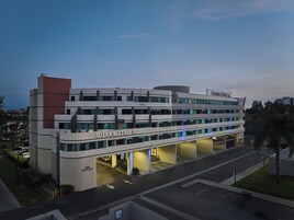 Un hotel moderno con varios pisos, un llamativo letrero de "DoubleTree" y un estacionamiento al frente.