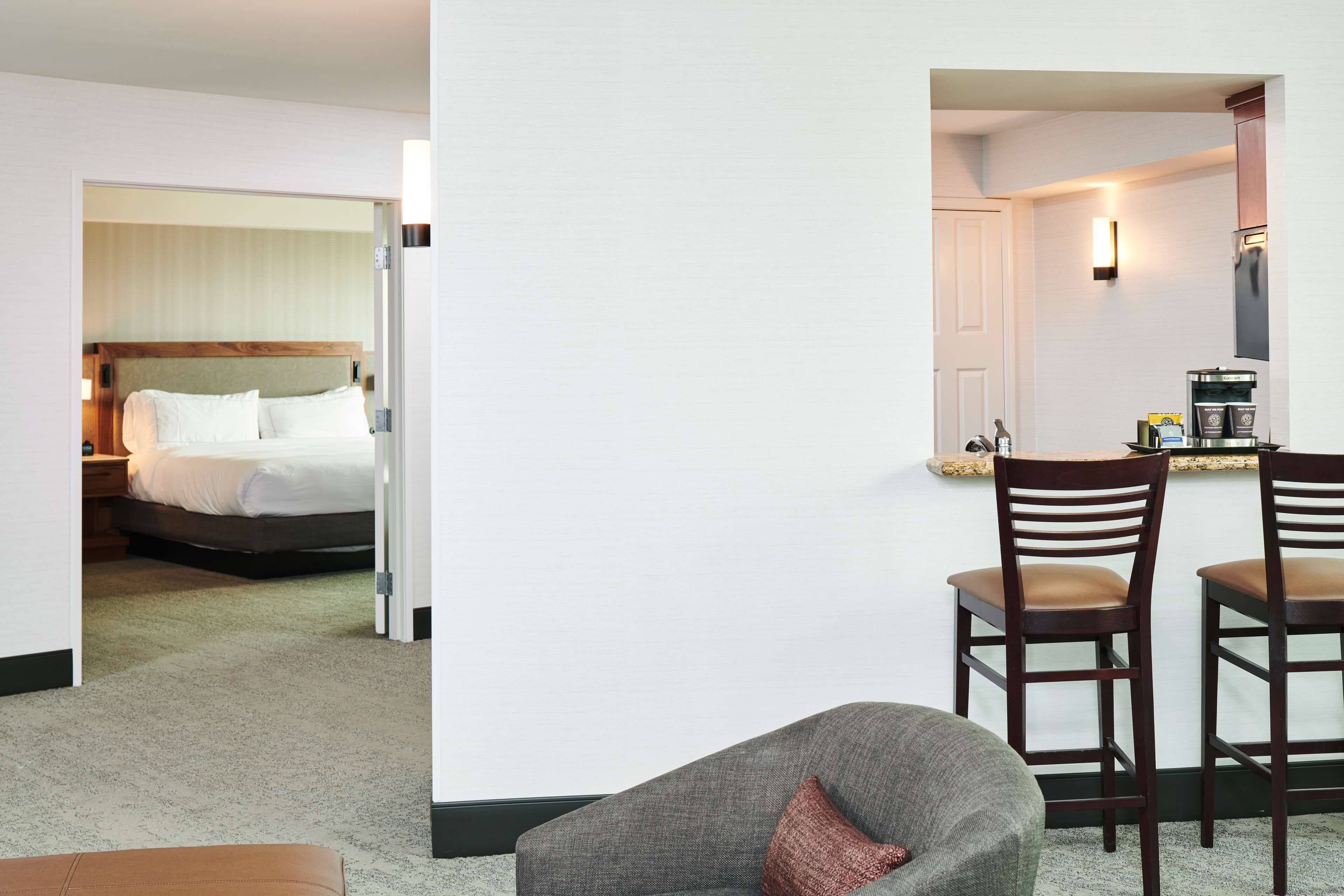 A hotel room with a bed, a desk with chairs, and a kitchenette.