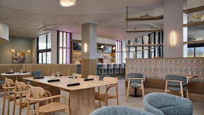 A modern restaurant with wooden tables and chairs, a bar area, and a view of the city. - DoubleTree by Hilton Fullerton (Fullerton)