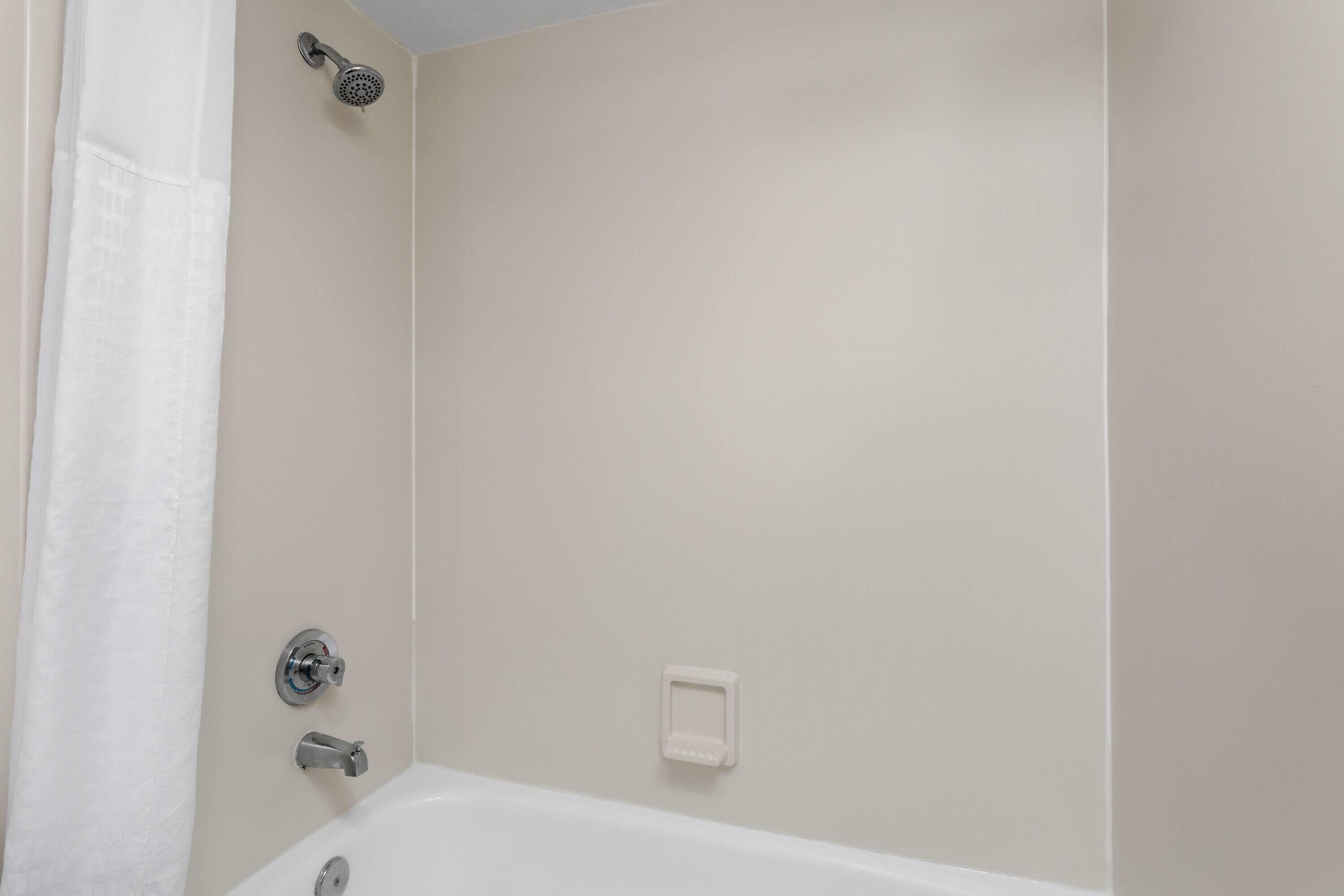 Un baño con bañera, cabezal de ducha y perchero.