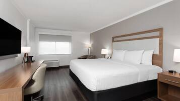Een hotelkamer met een bed, een bureau, een stoel, een televisie en een raam.