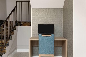 Un escalier avec une rampe en bois et un téléviseur noir posé sur un meuble en bois.