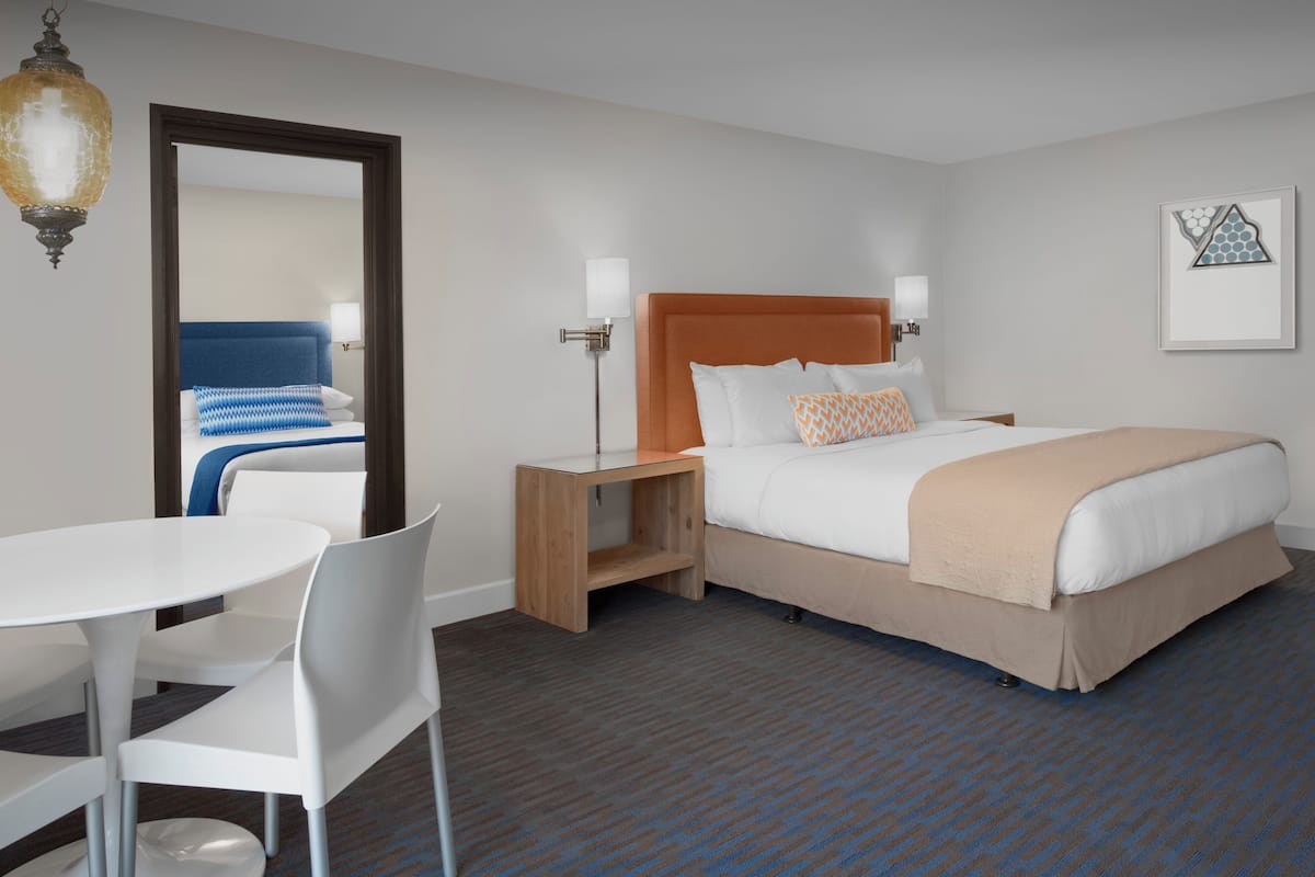 A hotel room with a bed, bedside tables, a desk, and chairs.