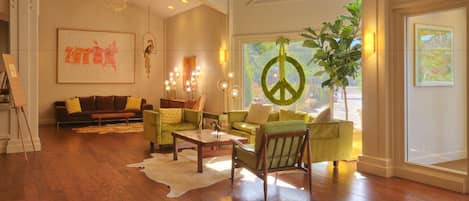 A spacious living room with hardwood flooring, a large window with a view, and a peace sign decoration.
