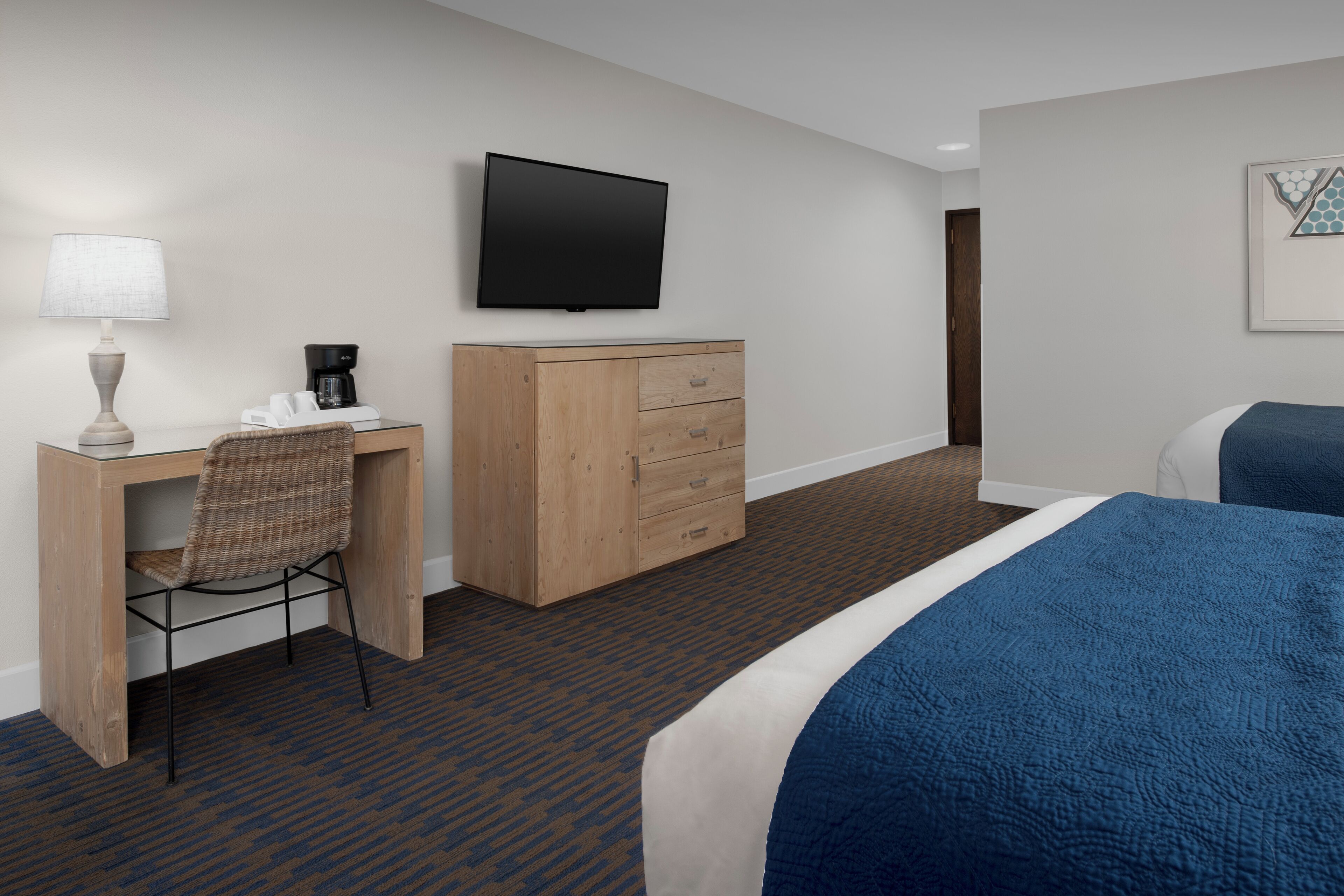 Una habitación de hotel con cama, escritorio, silla, televisor y armario.