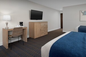 A hotel room with a bed, a desk with a chair, a television, and a wardrobe.
