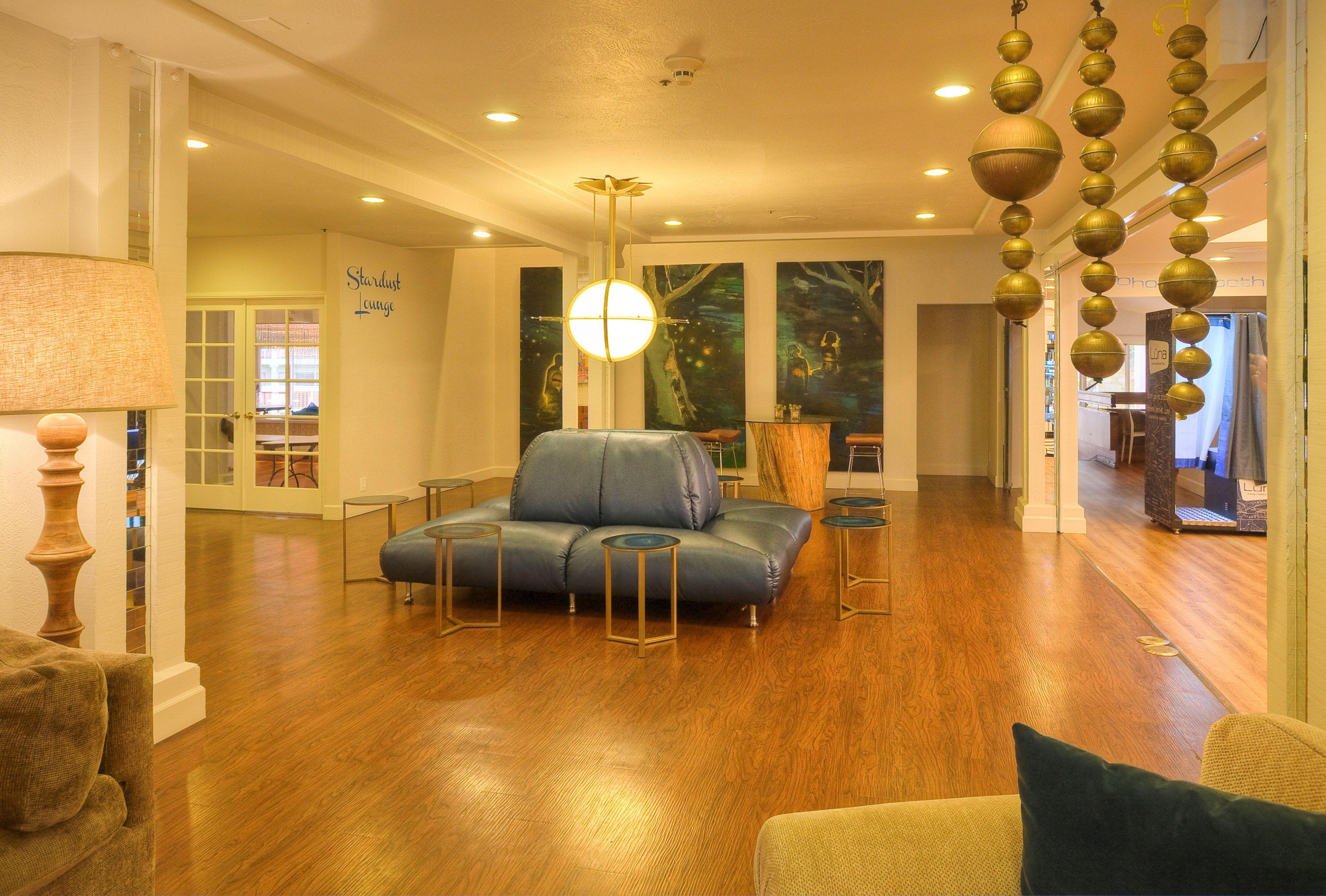A spacious living room with a blue sofa, wooden flooring, and a hanging spherical light fixture.