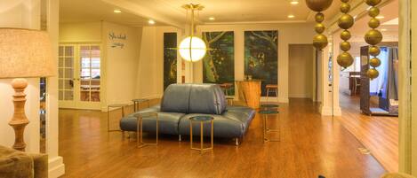 A spacious living room with a blue sofa, wooden flooring, and a hanging spherical light fixture.