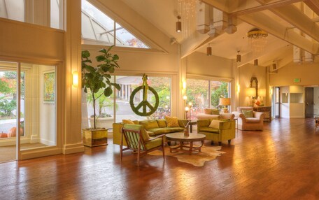 A spacious lobby with a large wooden floor, a green peace sign decoration, and a large window offering a view of the outdoors.