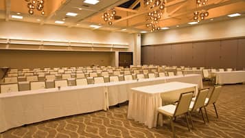 A large conference room with rows of tables and chairs, a patterned carpet, and hanging spherical light fixtures.