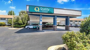 Un hotel con un letrero grande que dice "Quality Inn & Suites by Choice Hotels" y un estacionamiento con varios coches.