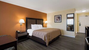 Habitación de hotel con una cama, dos lámparas de noche, una mesita de noche, un escritorio y una silla.