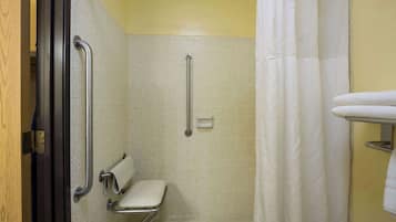 A bathroom with a wheelchair-accessible shower, a toilet with grab bars, and a towel rack.