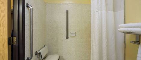 A bathroom with a wheelchair-accessible shower, a toilet with grab bars, and a towel rack.