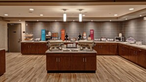 A modern hotel kitchen with a central island, wooden cabinets, and various food service equipment.