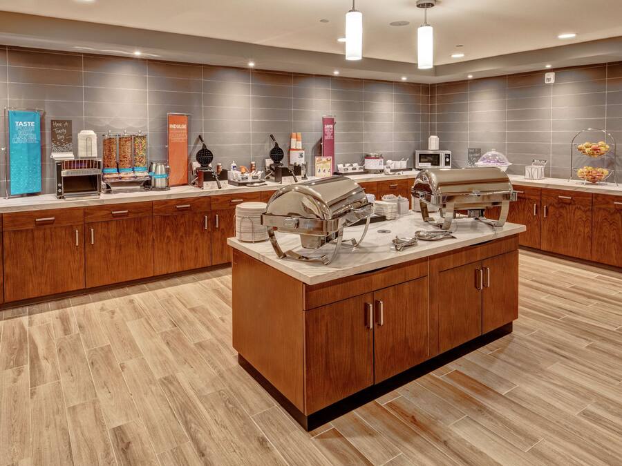 A modern hotel kitchen with a central island, various appliances, and a buffet setup.