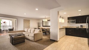 A modern living room with a sofa, ottoman, and a dining area with a table and chairs. - Homewood Suites by Hilton Tucson/St. Philip's Plaza Univ (Tucson)