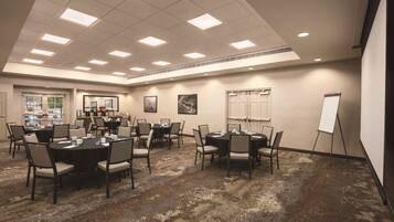 A conference room with round tables, chairs, a whiteboard, and a carpeted floor.