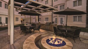 An outdoor patio with a fire pit, outdoor seating, and a covered area with umbrellas. - Homewood Suites by Hilton Tucson/St. Philip's Plaza Univ (Tucson)