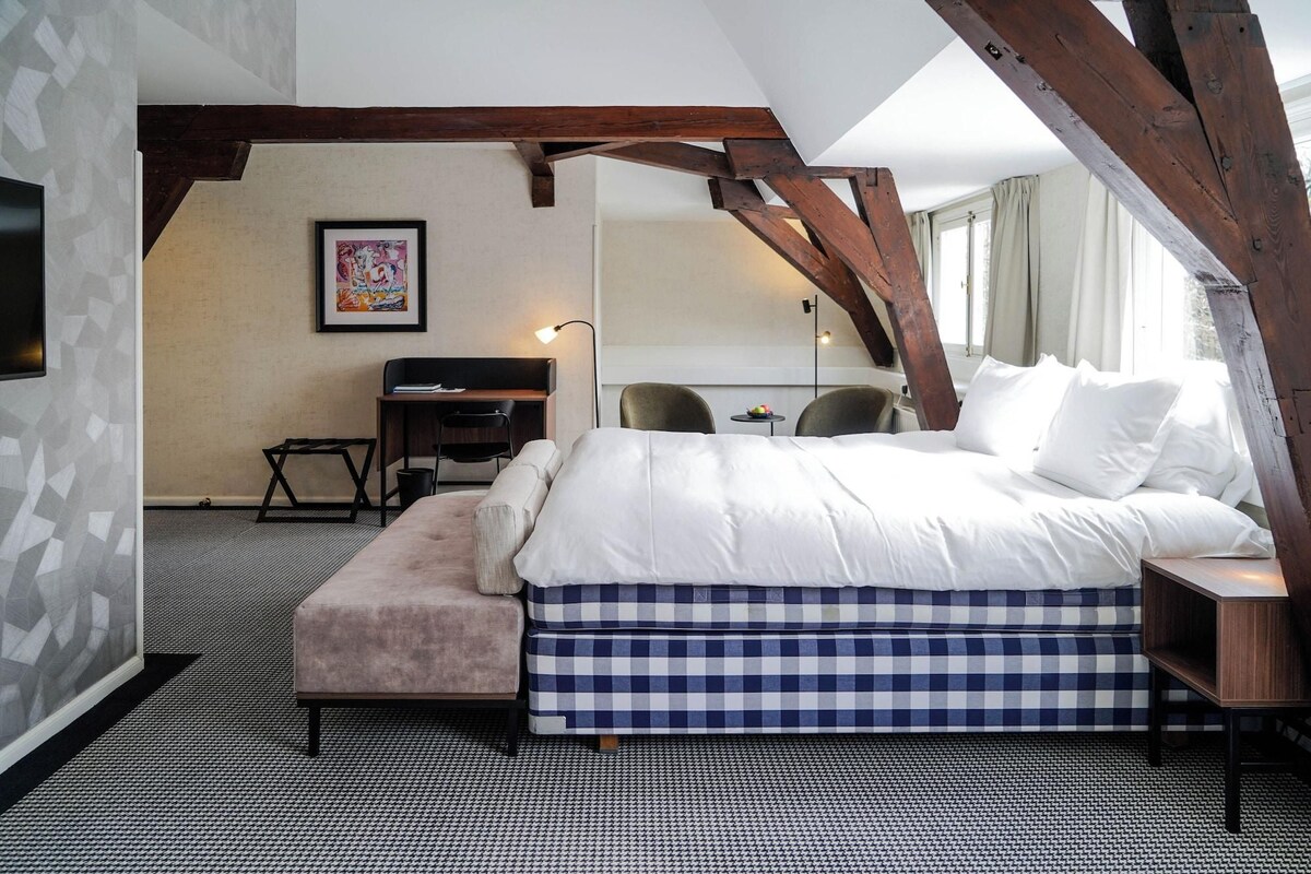 Een slaapkamer met een bed, een bureau, een stoel en een klein tafeltje.