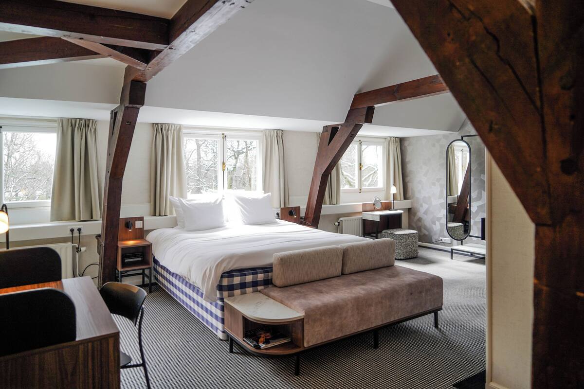 Een slaapkamer met een groot bed, een bank, een bureau en een spiegel.