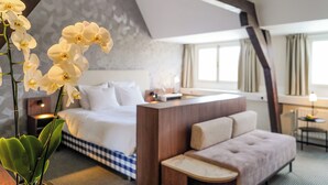 Et hotelværelse med en seng, en sofa, et lille bord og en dekorativ orchidé.