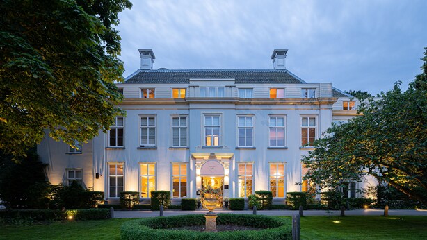 En stor, imponerende bygning med en symmetrisk facade, mange vinduer og en midterliggende indgang.