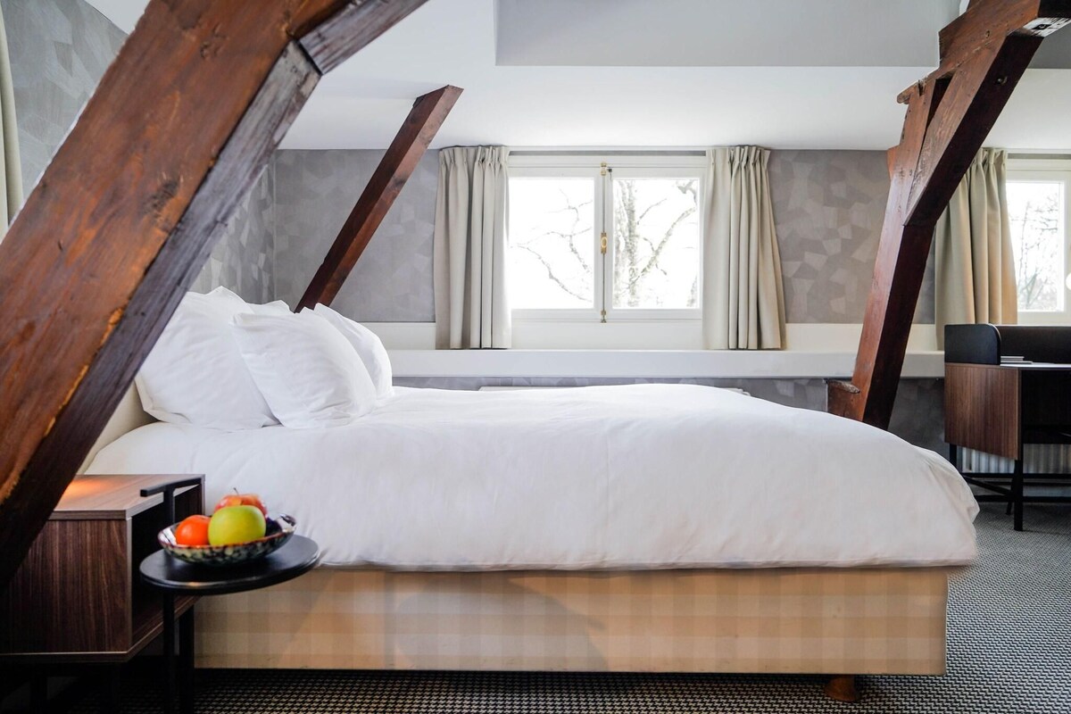 Een hotelkamer met een bed, een nachtkastje met een schaal fruit en een bureau met een stoel.