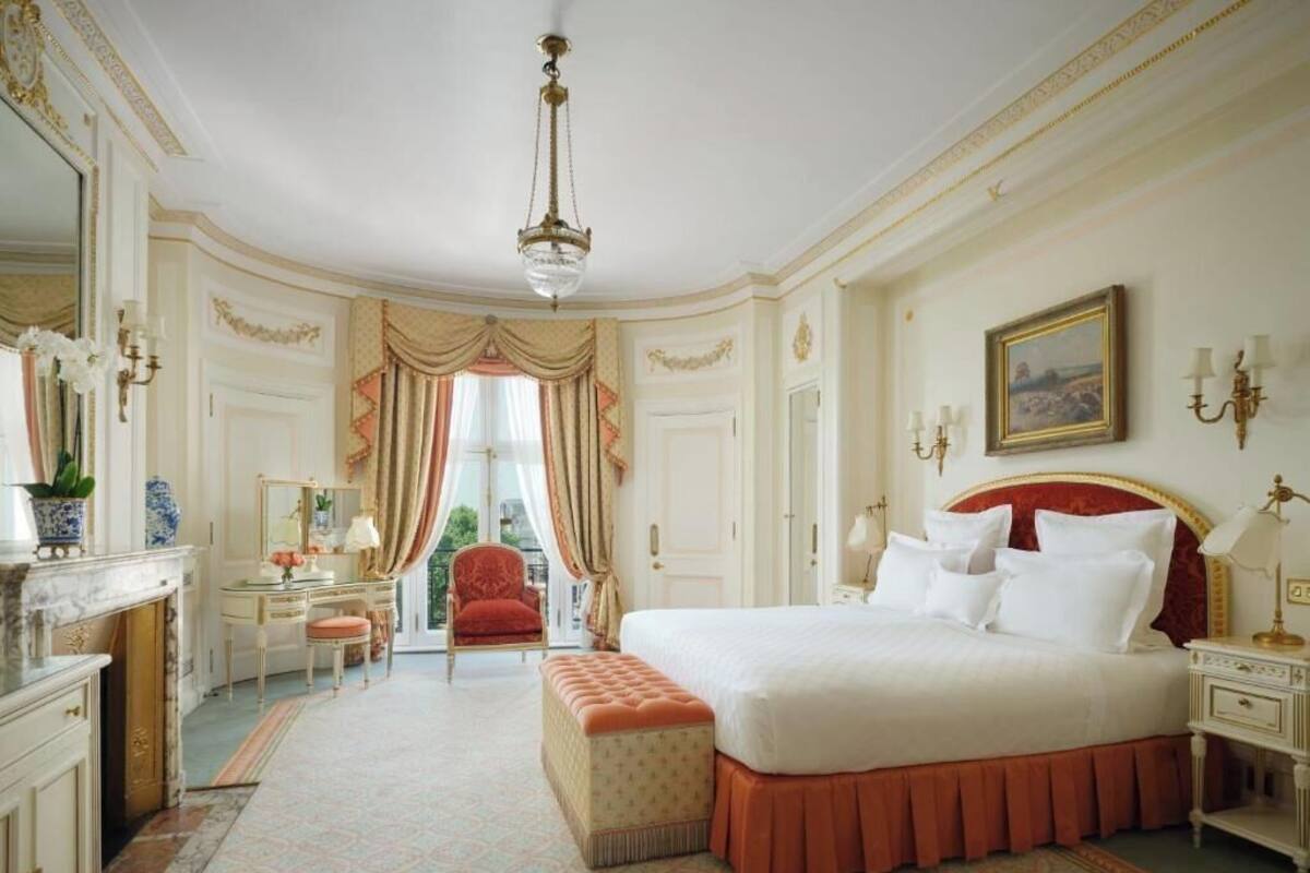 A spacious bedroom with a large bed, a sitting area, and a view of the outdoors.