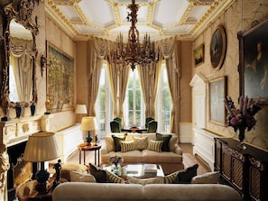 Una habitación lujosa con candelabro, muebles ornamentados y pinturas clásicas.