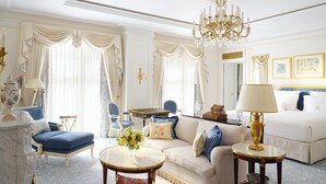 Une chambre luxueuse avec un canapé, une table basse ronde, un lit et un lustre.
